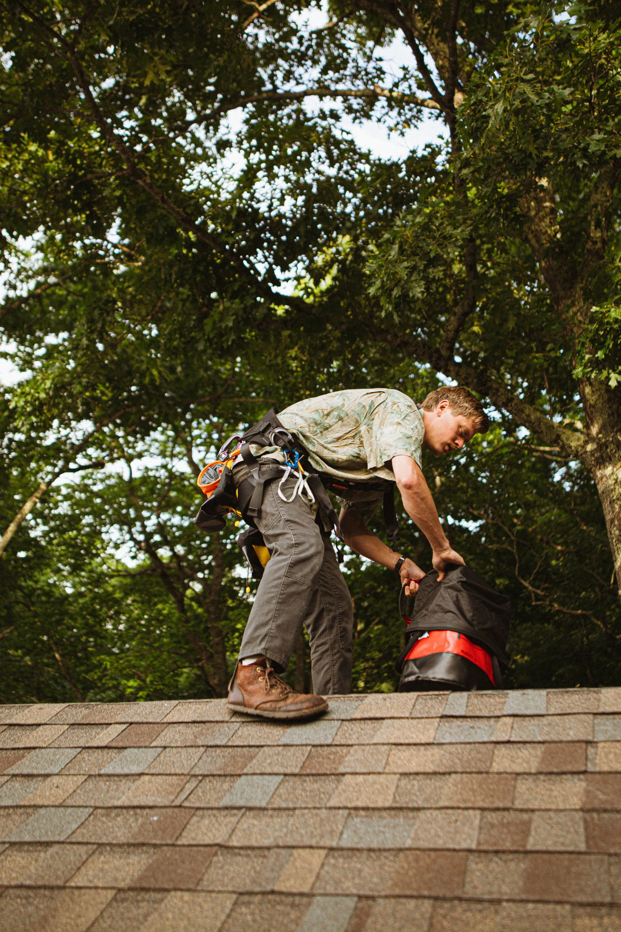 A roofer clearing a run of asphalt shingles with a blower