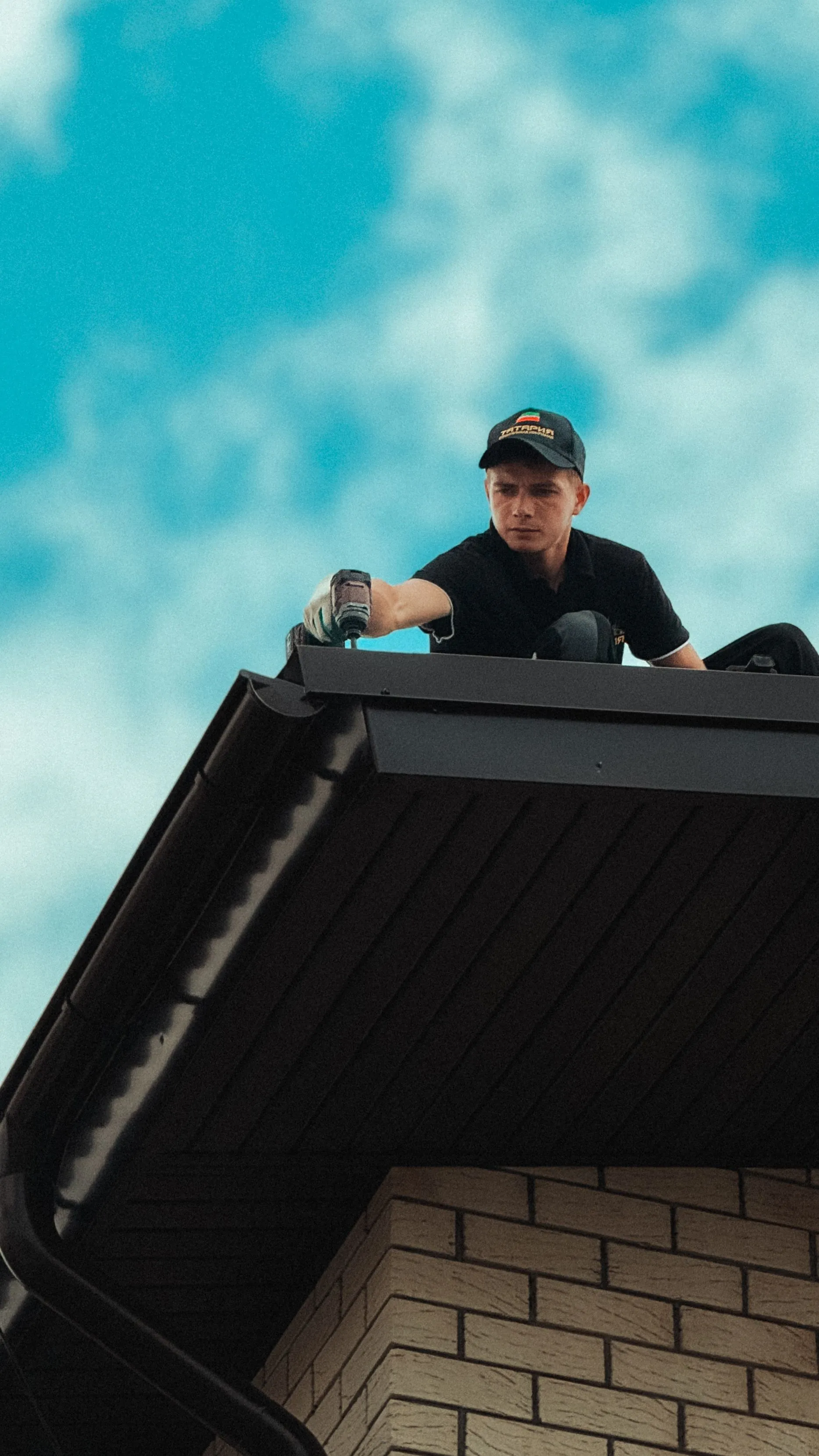 A roofer leaning over the eaves of a house against an open sky