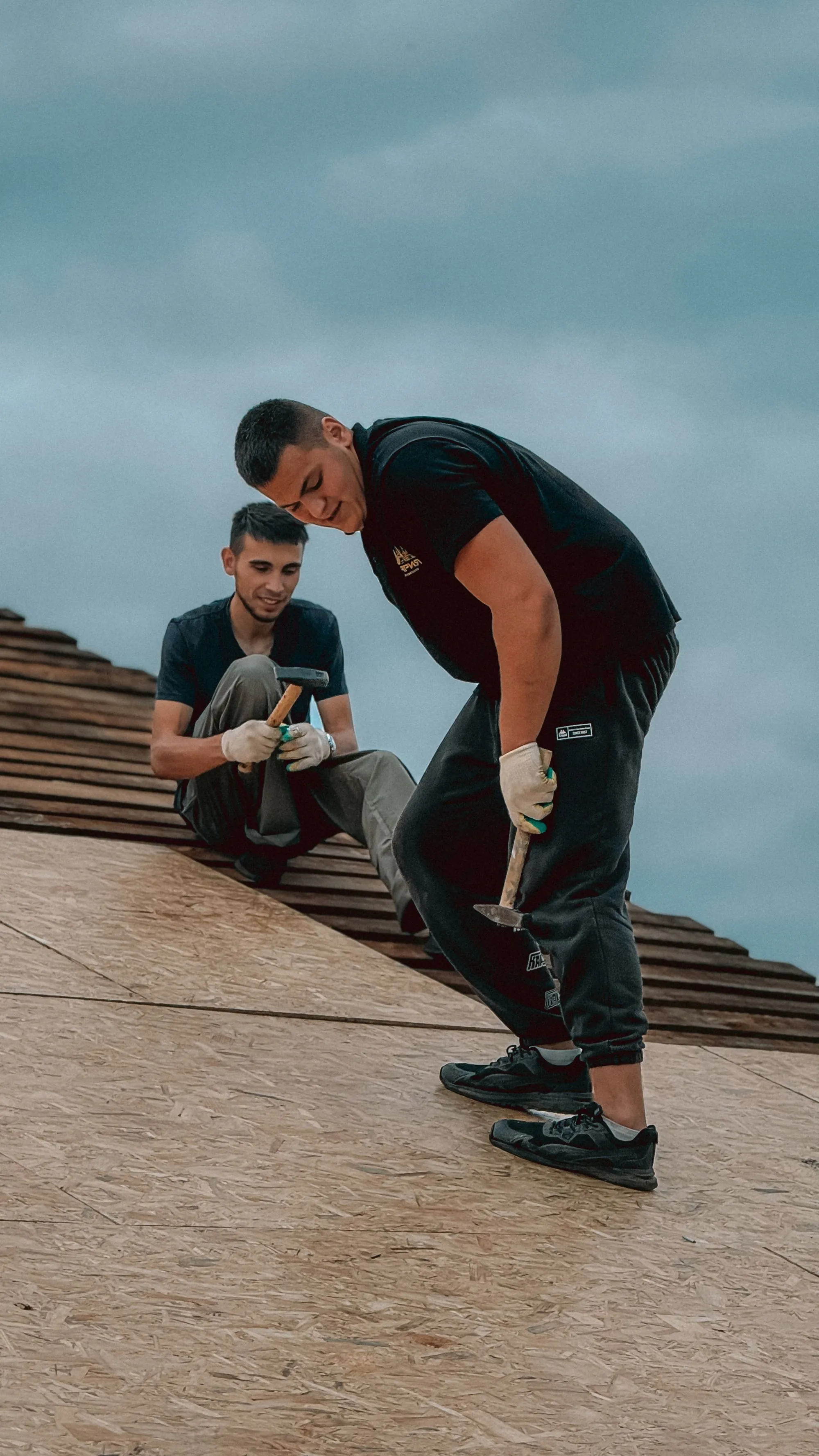 Two roofers working together across a sheet of roof decking