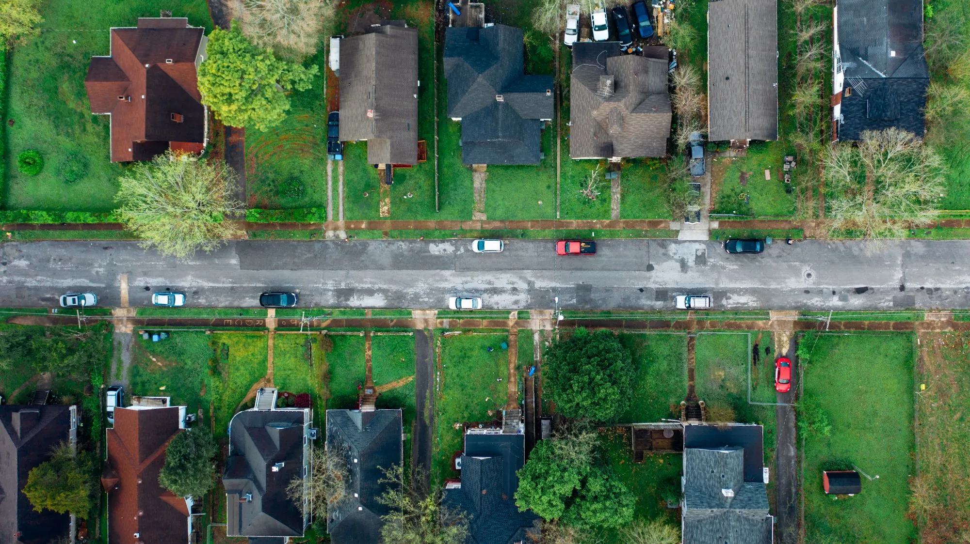 An aerial view of a suburban street of houses, lawns and driveways